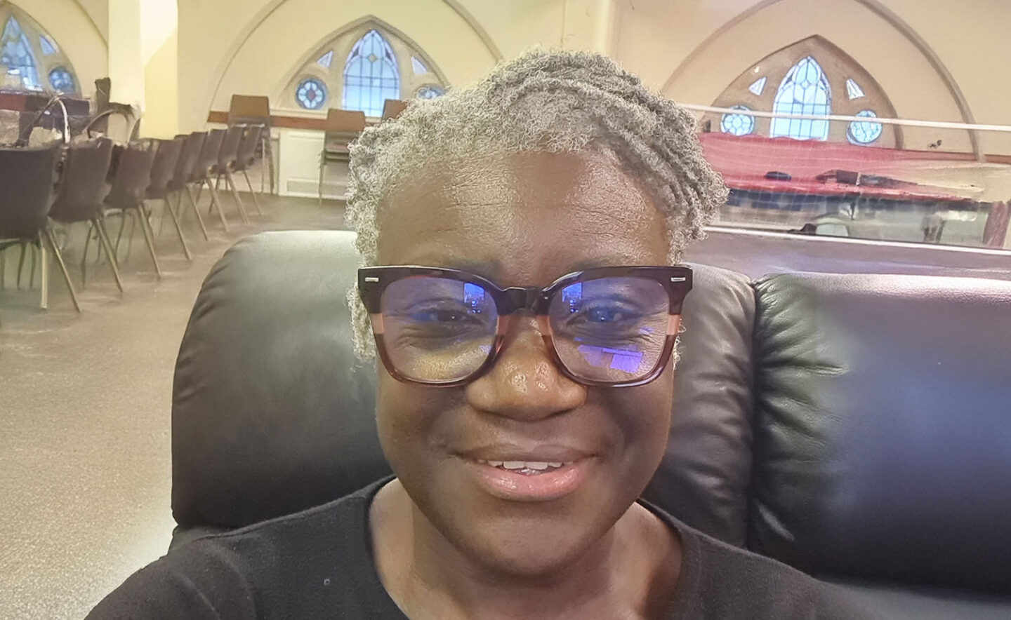 Headshot of Brenda Melhado - a Black woman with short, grey hair and glasses, wearing a black top.