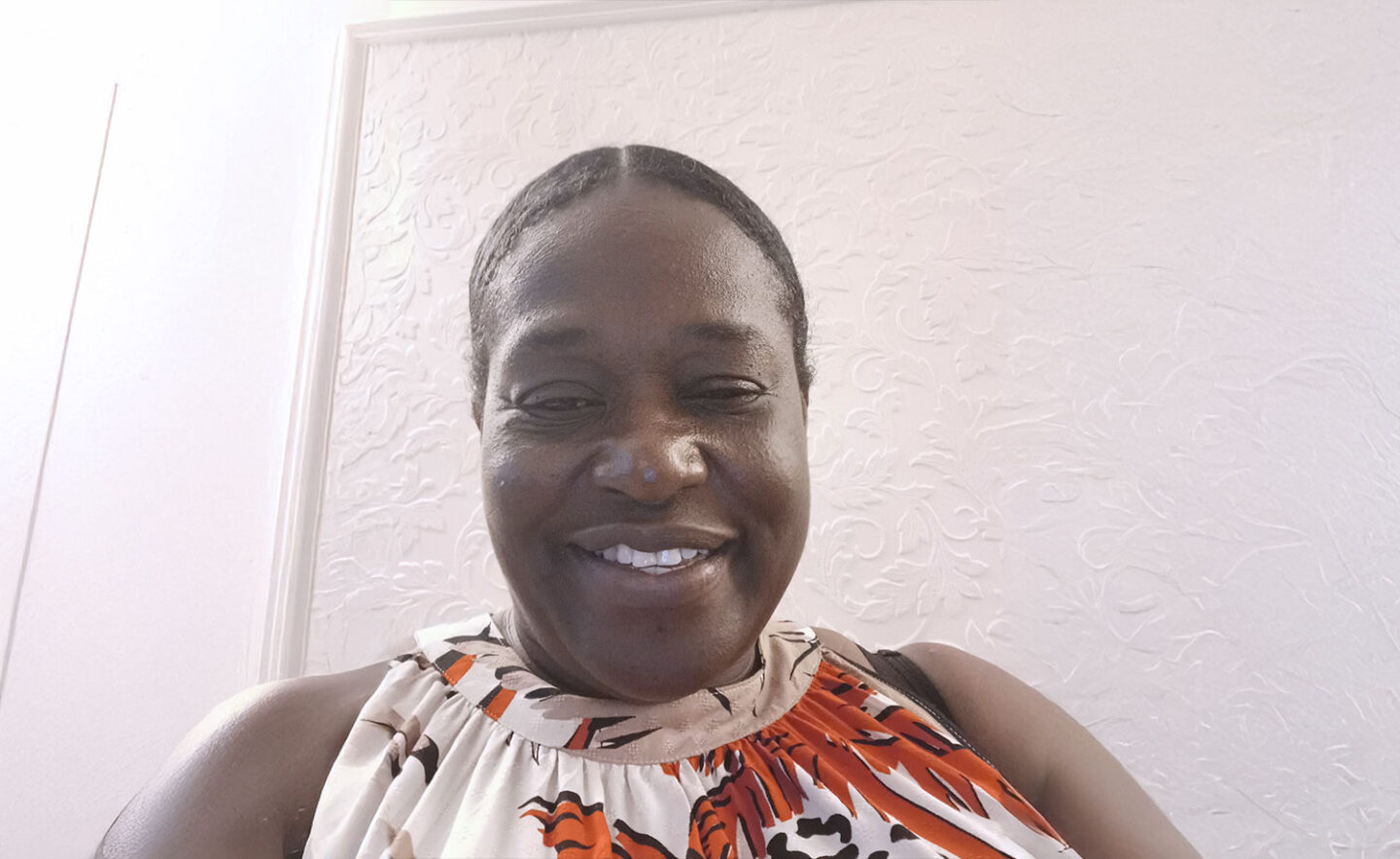 Headshot of Cindy Mardenborough - a smiling Black woman with her hair tied back, wearing a colourful patterned top.