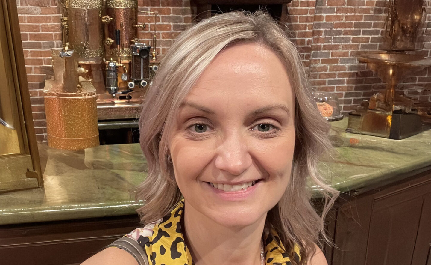 Headshot of Suzie Duncan - a smiling white woman with blonde hair and a yellow top.