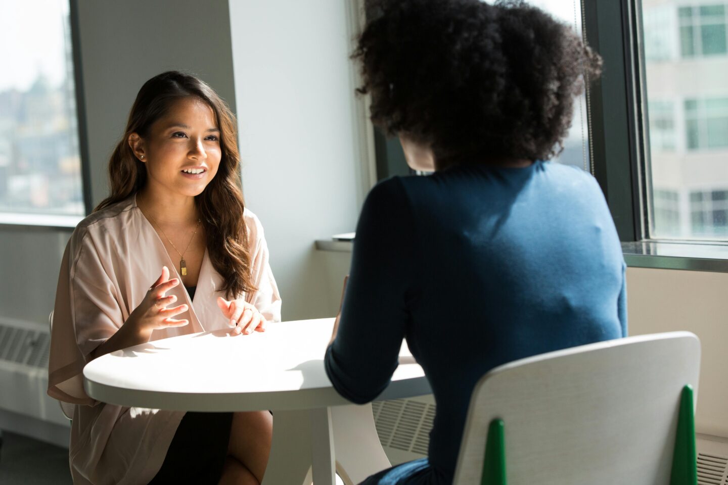 Two women chat in a coffee-morning style setting. The atmosphere is relaxed and they look comfortable.